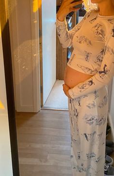 a pregnant woman taking a selfie in the mirror while wearing pajamas and holding a cell phone