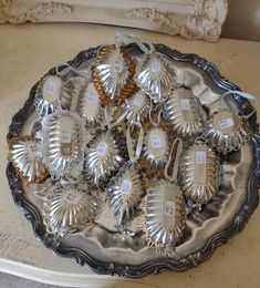 a silver platter with nine pairs of shoes on it and price tags in the middle