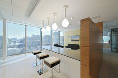 an empty office with stools and tables in front of large windows overlooking the city