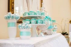 a table topped with lots of cupcakes covered in frosting and blue ribbons