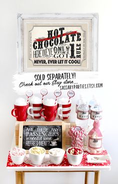 a red and white table topped with cups filled with hot chocolate next to a sign