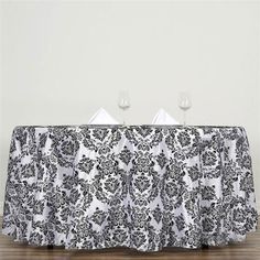 two wine glasses sitting on top of a table covered in black and white damask