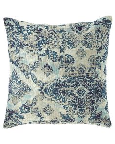 a blue and white pillow with an ornate design on the front, sitting on a white background