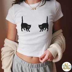 Nostalgic 90s baby tee with a three eyed black cat.  PLEASE NOTE THIS IS NOT A CROP TOP. PLEASE READ THE SIZE GUIDELINES IN THE PHOTOS. ❤ Made with 100%, midweight (5.3 oz/yd² (180 g/m US cotton that feels soft to the      touch and a great choice for any season. ❤ The crew neckline along with the tee's classic fit, deliver a timeless style that is       perfect for daily use. ❤ All t-shirts come with pearlized, tear-away labels for total comfort and a scratch-       free experience. ❤ Made usin Y2k Crew Neck T-shirt With Cat Print, Cotton Cat Print Tops For Streetwear, Cotton Tops With Cat Print For Streetwear, Y2k Cotton Cat Print Tops, Y2k Cat Print Crew Neck T-shirt, Y2k Style Cat Print Crew Neck T-shirt, Fitted Short Sleeve Tops With Cat Design, Y2k Cotton Top With Cat Design, Y2k Style Short Sleeve T-shirt With Cat Print