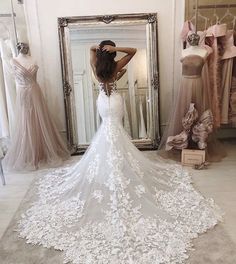 a woman standing in front of a mirror wearing a wedding dress with flowers on it