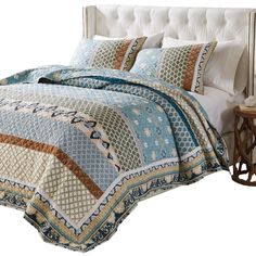 a bed with a blue and brown quilt on it