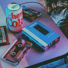 a table topped with cassettes and a can of coke