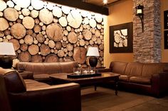 a living room with couches and tables in front of a wall made of logs