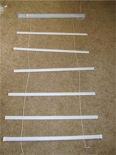 several strips of white paper are hanging on the wall next to each other with string attached