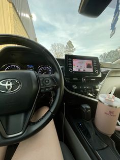 the interior of a car with dashboard, steering wheel and coffee cup on the dash