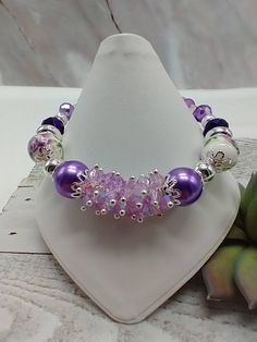 "Handmade by me-lilac glass crystal beads-lilac ceramic flower beads-various glass beads-fits a 7 1/4\" wrist-silver tone-lobster clasp-1\" extender chain-give to someone you know is a purple lover! Makes a statement when wearing!" Purple Beaded Bracelets With Watch, Lavender Bracelets With Spacer Beads As Gift, Lavender Bracelets With Spacer Beads For Gift, Purple Flower-shaped Beaded Bracelets, Purple Flower Shaped Beaded Bracelets, Purple Beaded Flower Bracelets, Lavender Beaded Crystal Bracelet As A Gift, Lavender Beaded Crystal Bracelet For Gifts, Adjustable Purple Flower Beaded Bracelets