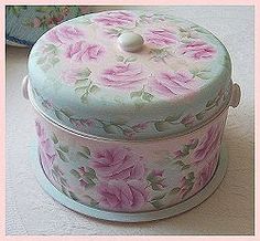 a pink and white flowered box with lid on a table next to a purse