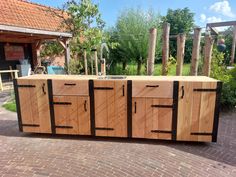 a kitchen island made out of wood and metal bars on top of brick patio area