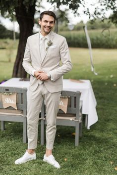 a man in a suit standing next to a table with white linens on it