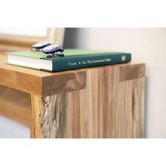 two books sitting on top of each other on a wooden table next to a mirror