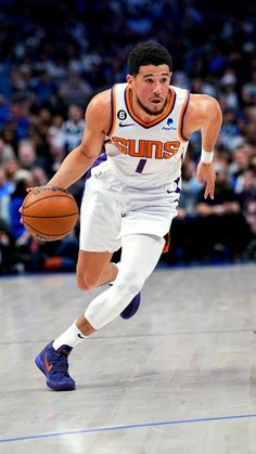 a basketball player dribbling the ball during a game with an audience in the background