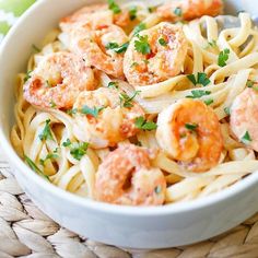 pasta with shrimp and parsley in a white bowl on a woven place mat next to a green napkin