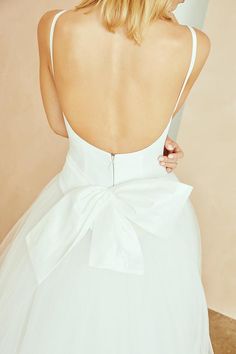 a woman in a white dress with a big bow on her back