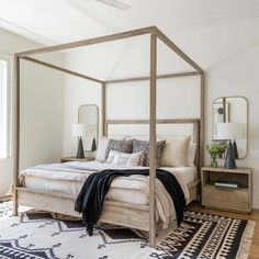 a bedroom with a four poster bed, rug and mirror on the wall next to it