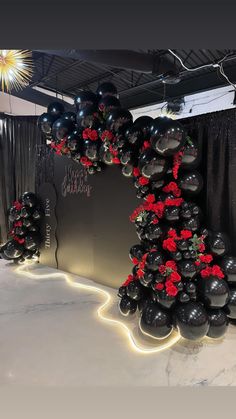 black and red balloons are arranged in the shape of a christmas tree on a stage