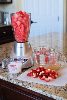 a blender filled with strawberries on top of a counter next to other ingredients