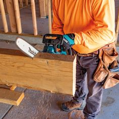 a man holding a power tool in his right hand while standing next to a piece of wood