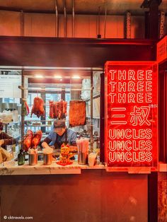 a neon sign in front of a food stand with meat hanging from it's sides