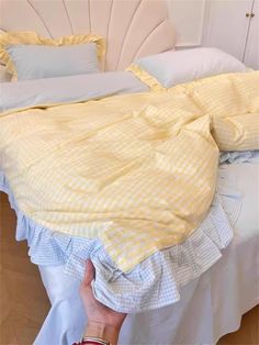 a bed with yellow and white bedspread on top of it next to pillows