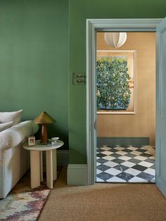 an open door leading to a living room with green walls and checkered flooring