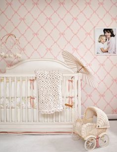 a baby's room with pink wallpaper and a white crib in the foreground