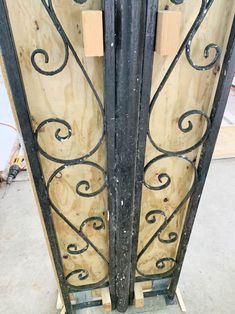 an iron gate with wooden planks on the bottom and sides that have been painted black