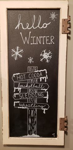 a chalk board with writing on it in front of a white wall and some snowflakes