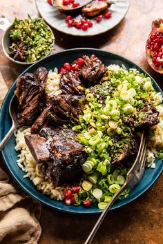 a blue plate topped with meat and rice next to pomegranate on a table