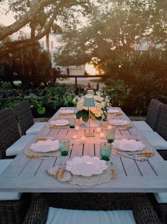 an outdoor table set with plates and candles