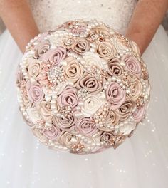 a bridal holding a wedding bouquet with pearls and pink roses on the bottom,