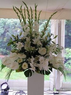 a vase filled with white flowers sitting on top of a table next to a window