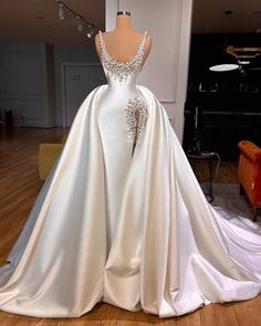 a white wedding dress on display in a room with wooden floors and furniture, including a mannequin