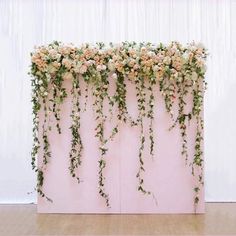 an arrangement of flowers and greenery is displayed on the side of a pink wall