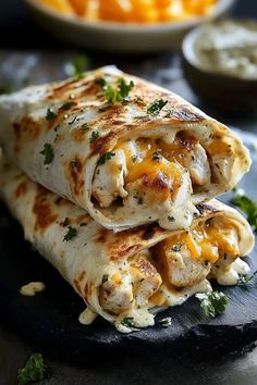 two quesadillas stacked on top of each other with cheese and vegetables in the background