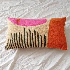 an orange and pink pillow sitting on top of a bed