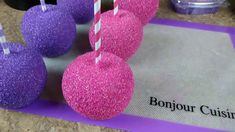 some pink and purple cake pops are on a mat