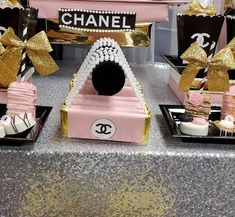 chanel themed desserts are on display at a party in pink, gold and black