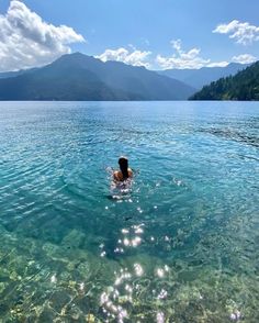 a person swimming in the water with mountains in the background