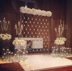 an elegant wedding setup with white flowers and chandelier hanging from the ceiling, surrounded by candles