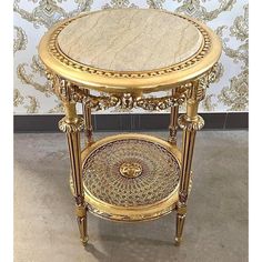 an ornately decorated gold side table with marble top and metal accents on the sides