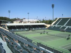 an empty tennis court is seen in this image from inside the stadium seats, looking toward the stands