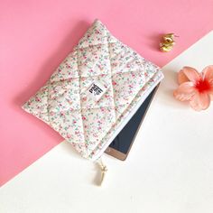 an ipad case sitting on top of a pink and white surface next to a flower