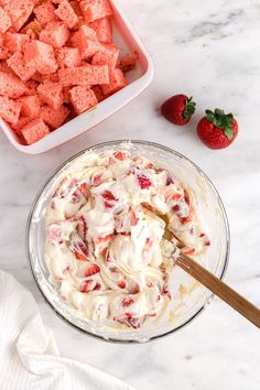 strawberry cheesecake dip in a glass bowl with strawberries on the table next to it