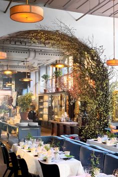 a restaurant with tables and chairs covered in white tablecloths, surrounded by greenery