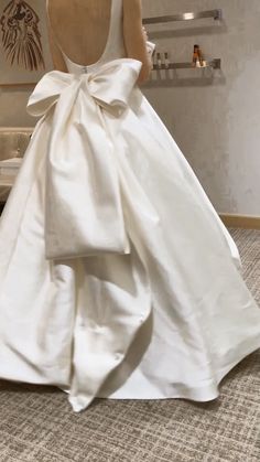 the back of a woman's wedding dress with a large bow on her waist